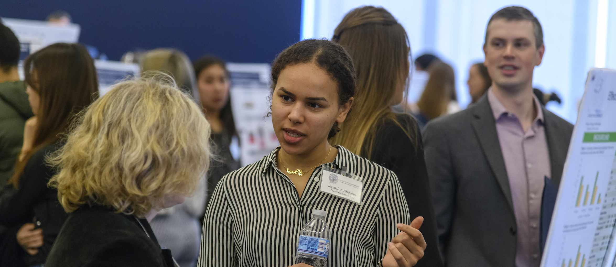 A student discusses her research with a conference attendee