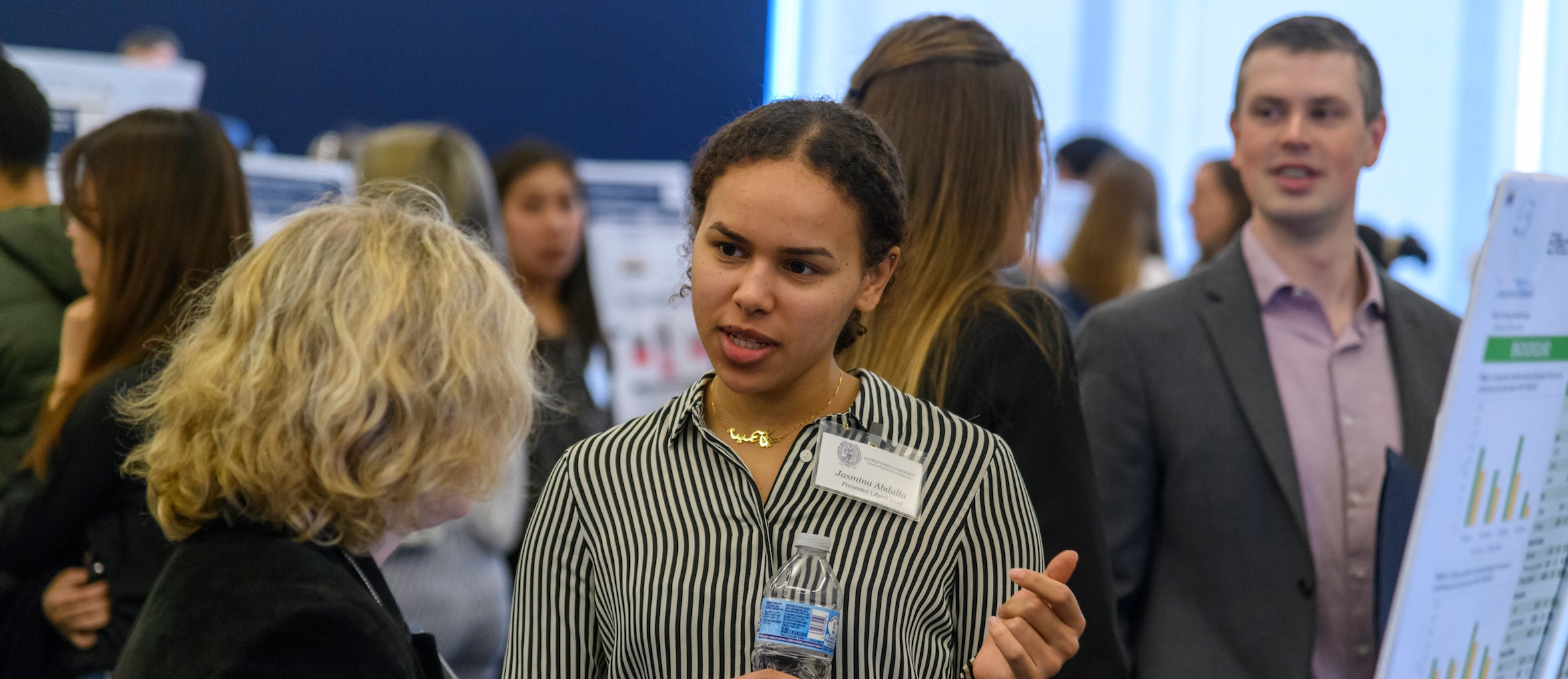 A student discusses her research with a conference attendee