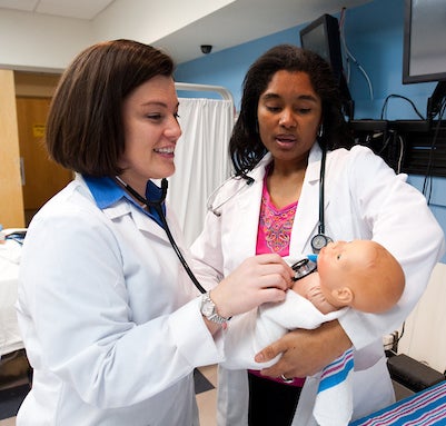 Two family nurse practitioner students work with a baby simulator in the Clinical Simulation Laboratory.