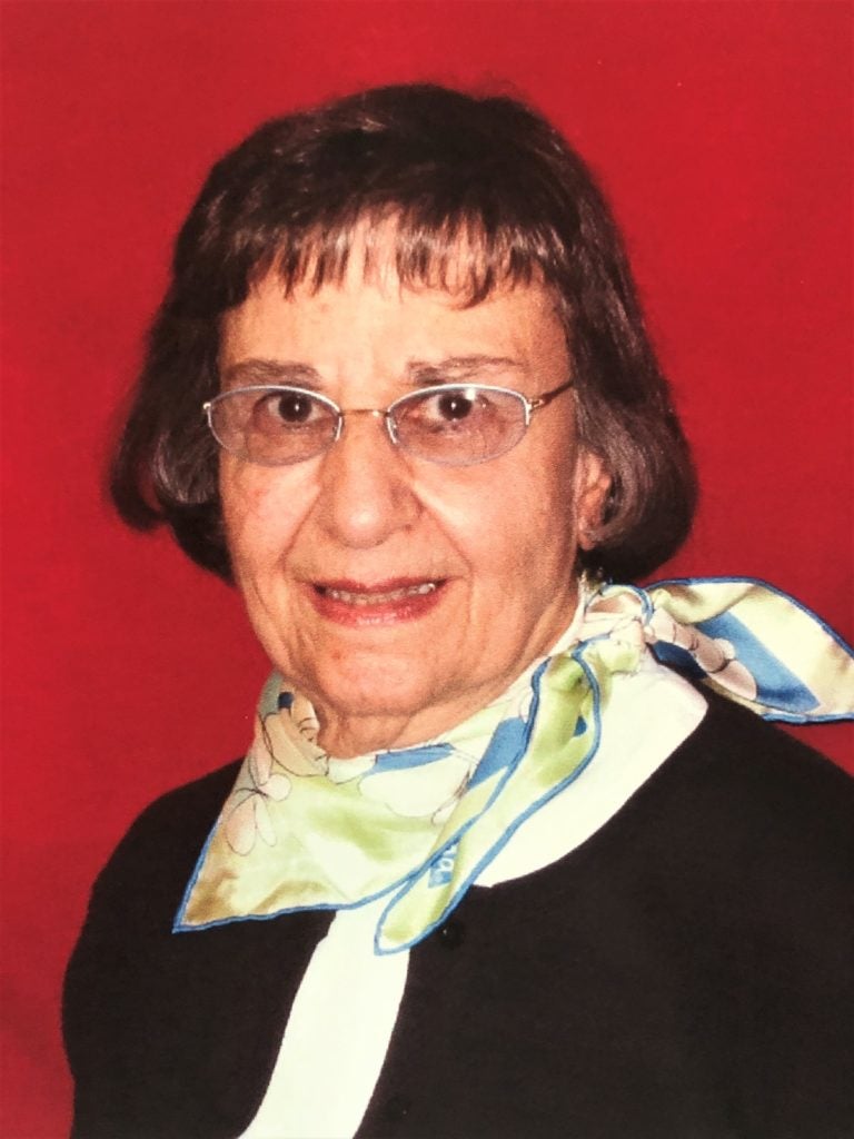 A headshot of Marie Bruce in front of a red background