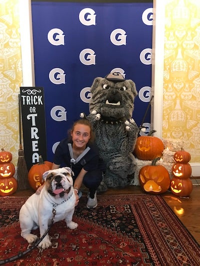 Alexandra Gladding, in her nursing uniform, poses with Jack the Bulldog and lit jack-o-lanterns at the Reed Residence.