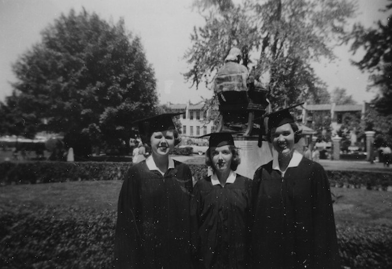 A black and white graduation photo from the mid-1950s with three graduates standing on Healy Lawn