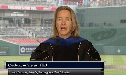 A screen shot of Dr. Carole Roan Gresenz speaking at the Georgetown Commencement with Nationals Park seats behind her.