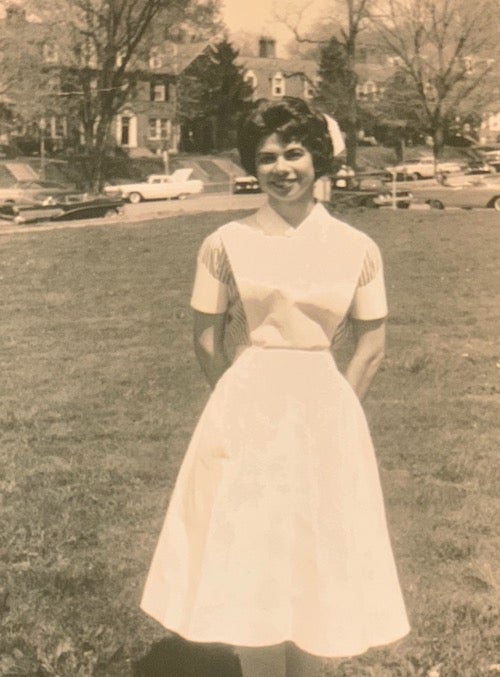 Georgetown BSN alumna Florence Mahoney of the Class of 1963 stands in her nursing uniform with Reservoir Road behind her.