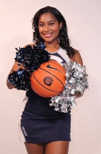 Alyssa Randall-Rose in her Georgetown cheer team uniform holding a basketball with the Georgetown "G" on it.