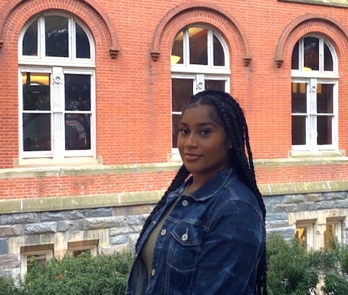 Alyssa Randall-Rose poses outside of Healy Hall on Georgetown's campus on the side of the building with red bricks and stone