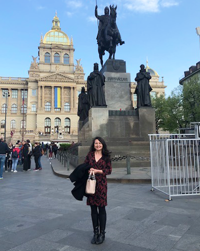 Kelley Anderson stands before a statue in a Prague square