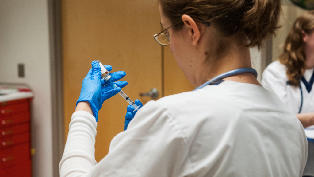 A nursing student prepares a syringe