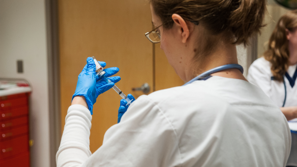 A nursing student loads a syringe