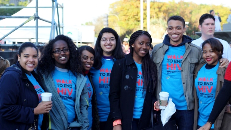 A group of students stand together wearing matching T-shirts that say Walk to End HIV