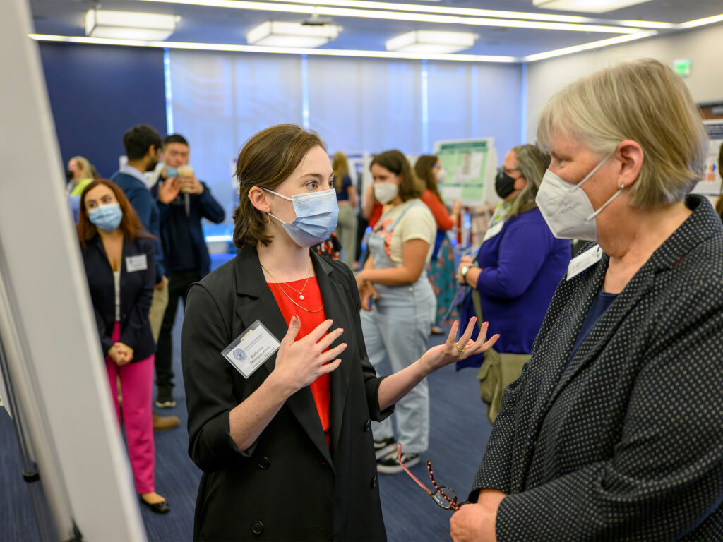 A student speaks to a professor at a poster session