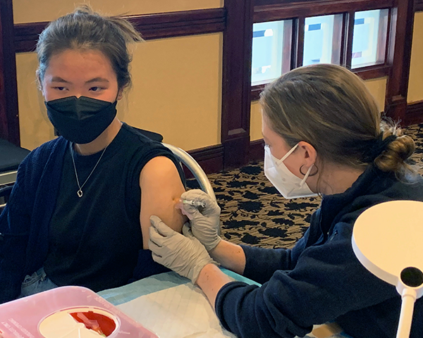 A student administers a flu shot to another student