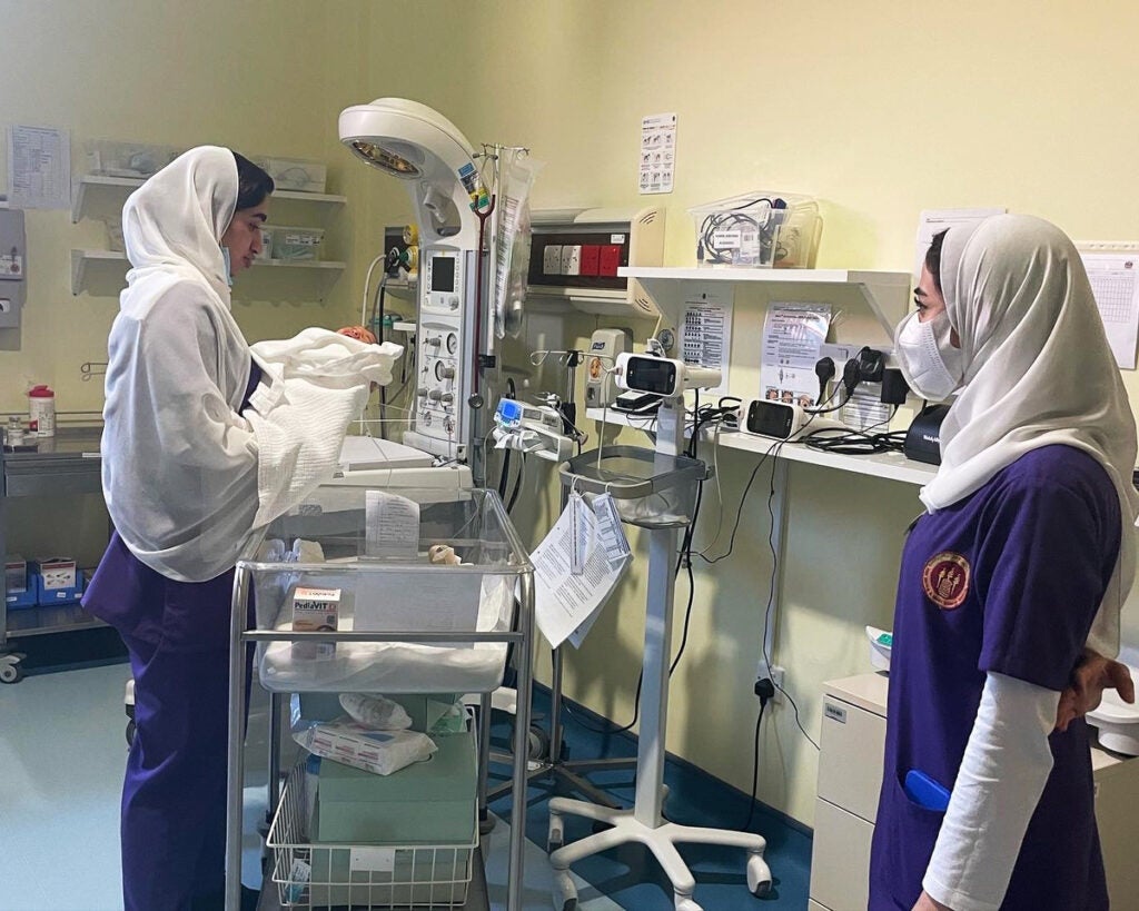 Two nurses tend to a baby in the nursery of a hospital in the UAE