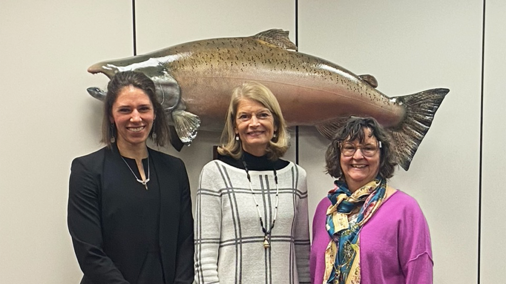 Three individuals stand in front of a large taxidermied fish