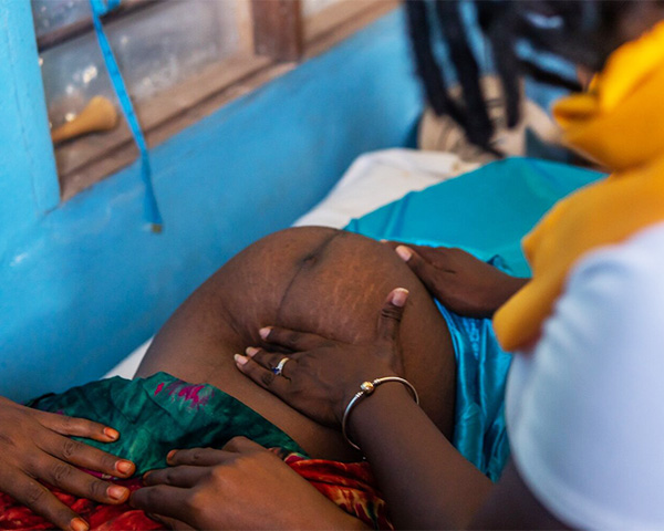A woman examines the belly of a pregnant woman