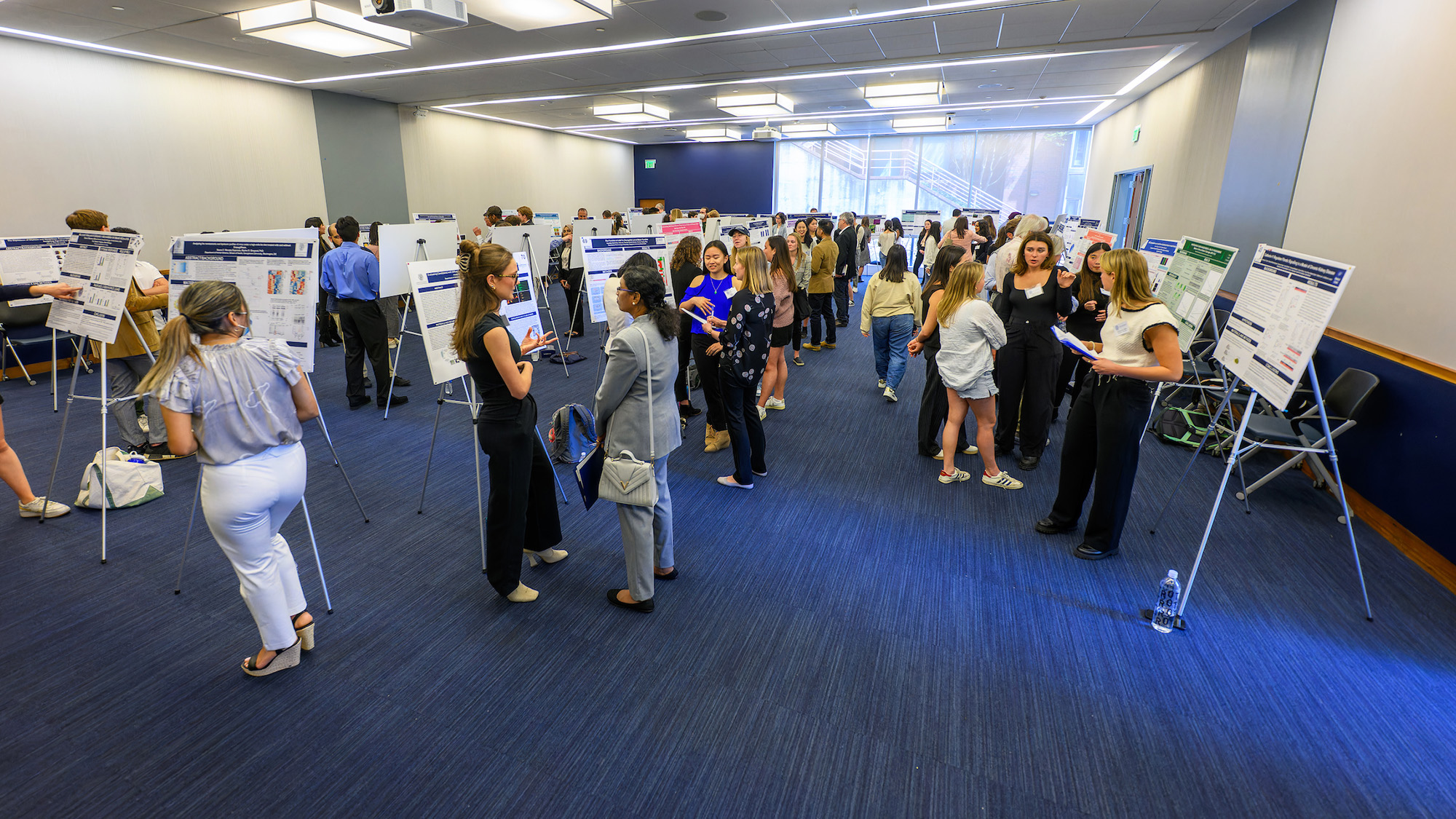 A crowd of people fill the room during the poster session for the Undergraduate Research Conference