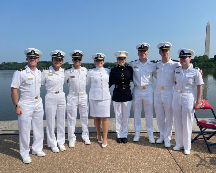 A group of newly commissioned Georgetown students stand in their Navy choker whites with the Washington Monument in the background