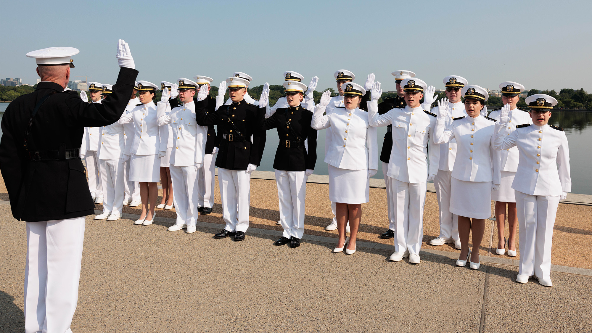A group of Navy ROTC students salutes a commanding officer as they are commissioned