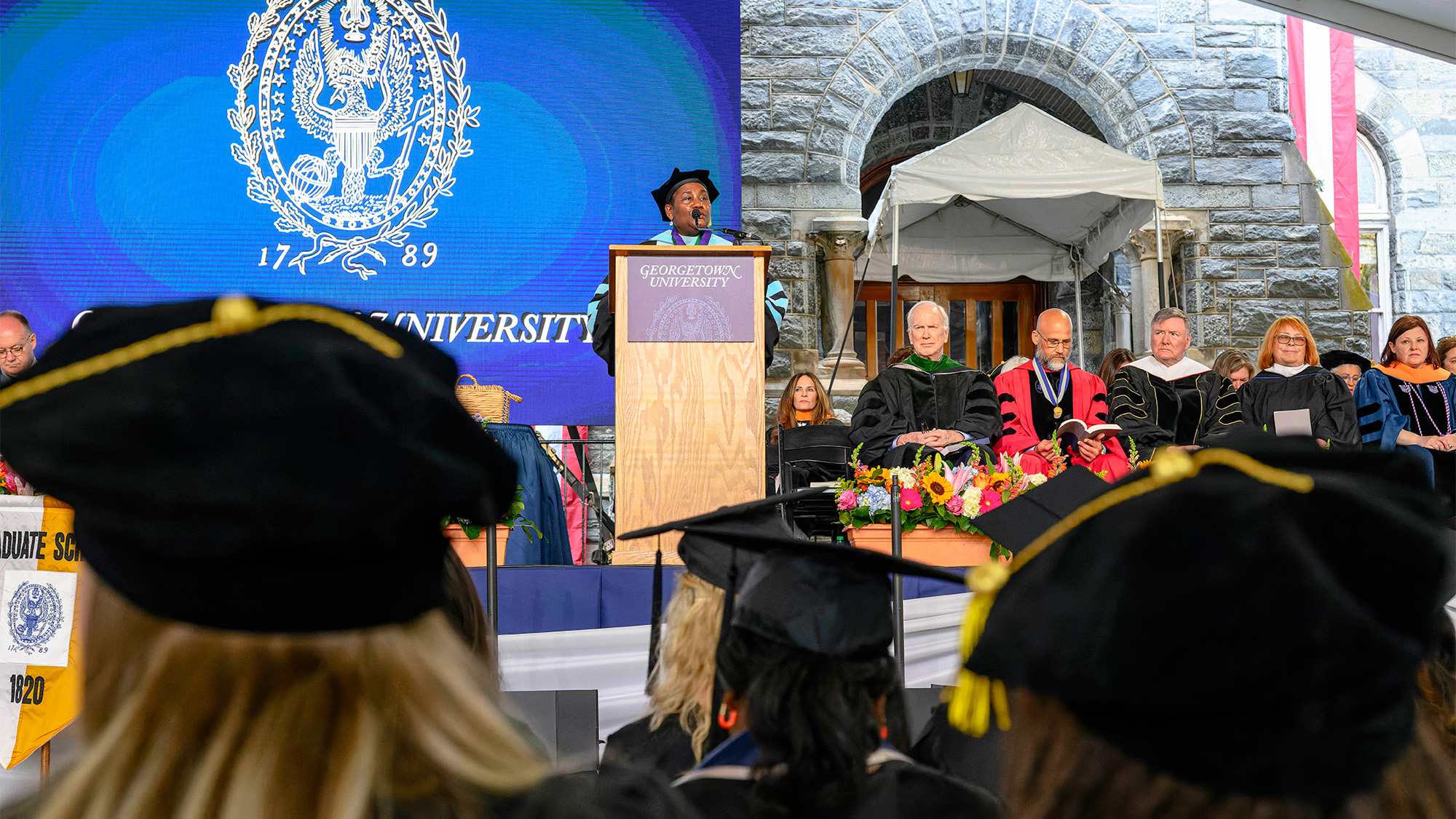 Dean Roberta Waite speaks at a podium before a group of graduating nursing students