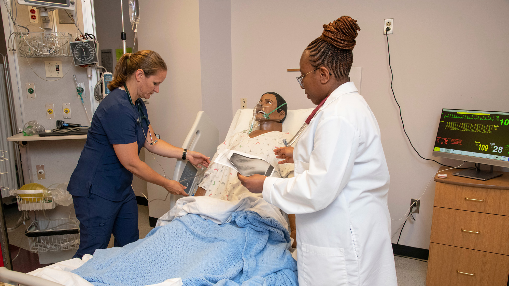 Nursing students tend to a patient simulator in the SIM Lab