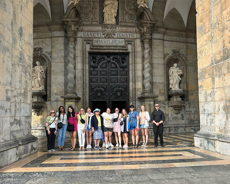 A group of people stand together in towering, marble- and statue-lined entrance to the basilica of the Sanctuary of Loyola 