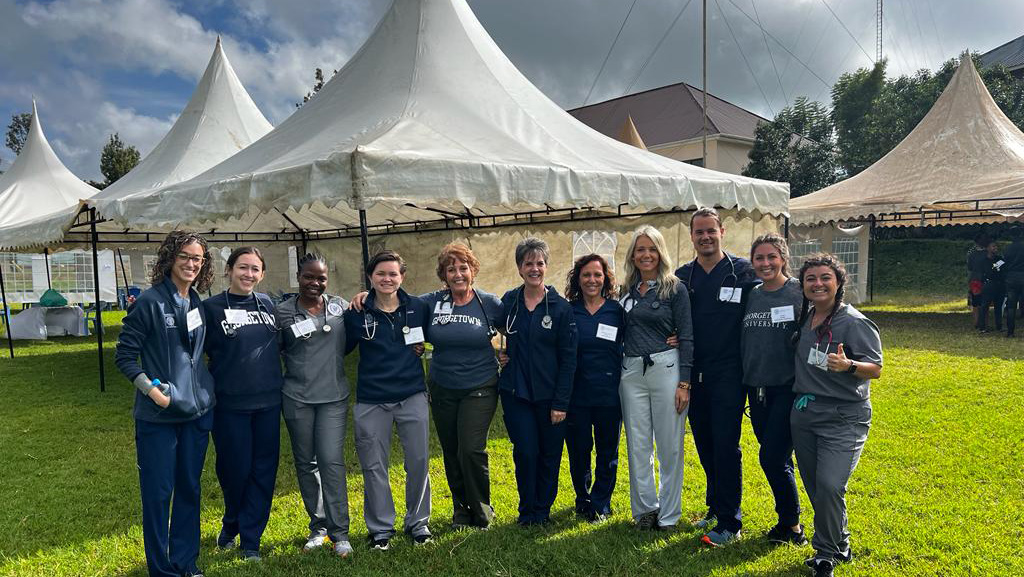 Students and faculty stand together in front of tents set up at the hospital they were visiting in Tanzania