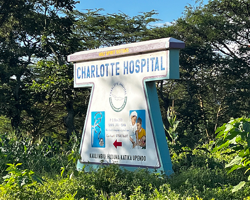 A sign reads Charlotte Hospital amid trees and lush plants