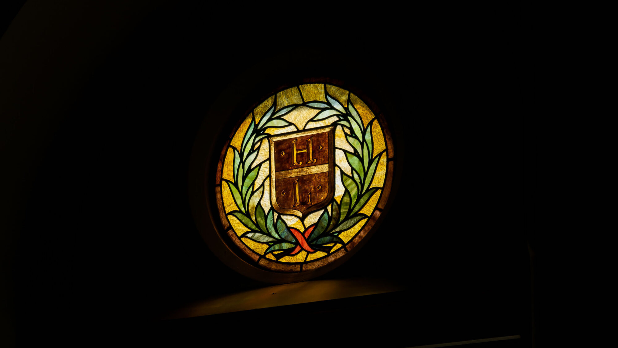 A stained glass window glows colorfully against a dark background