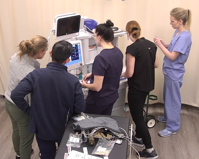 Five students assemble pieces for the anesthesia machine