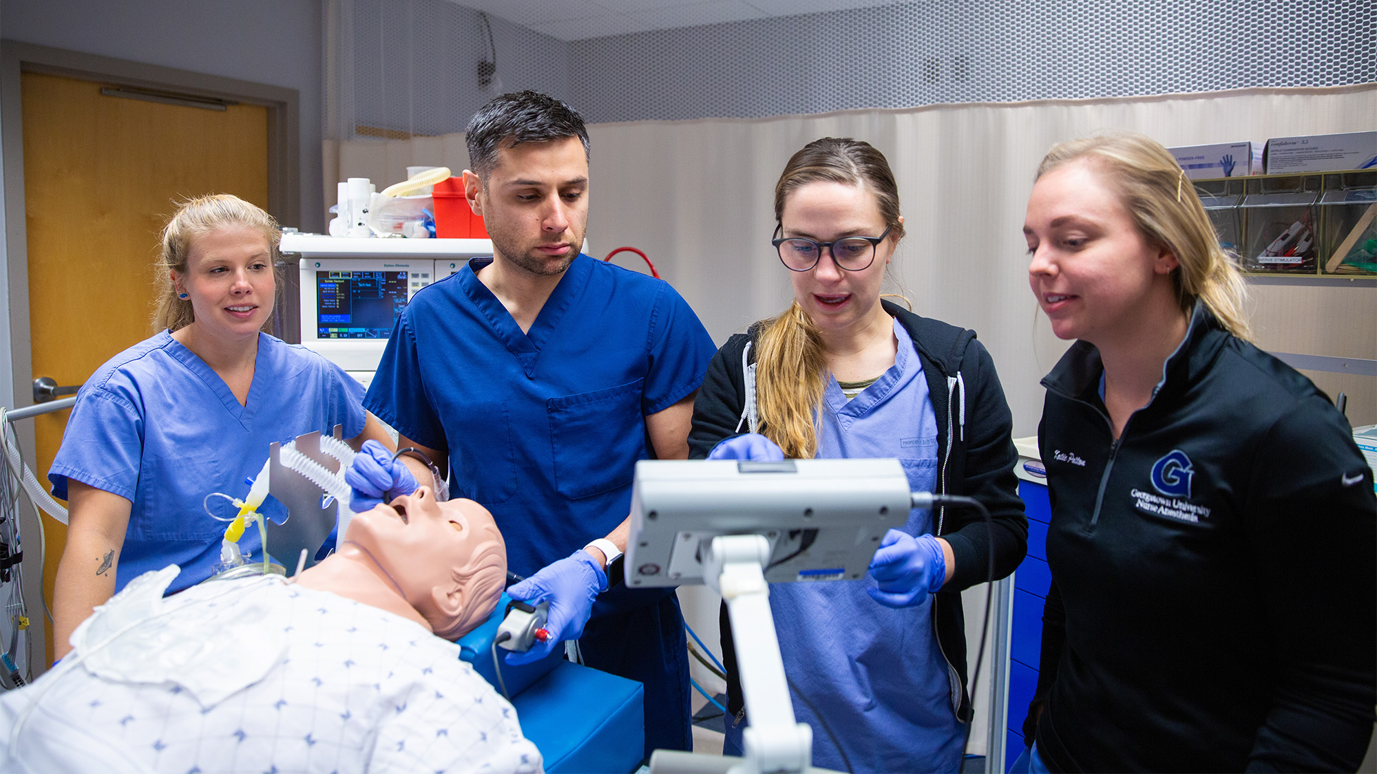 Four nurse anesthesia students work in the SIM lab using the GUS simulator