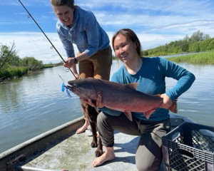 Lindsey Wagner and an Alaska Native woman pull a fish from the water