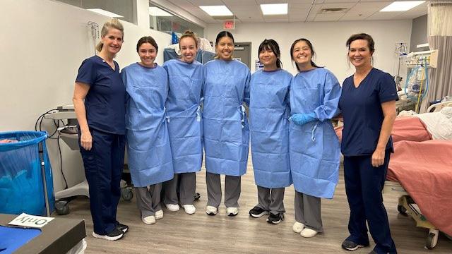 Nursing students in sterile coverings stand with their mentor nurses in the hospital