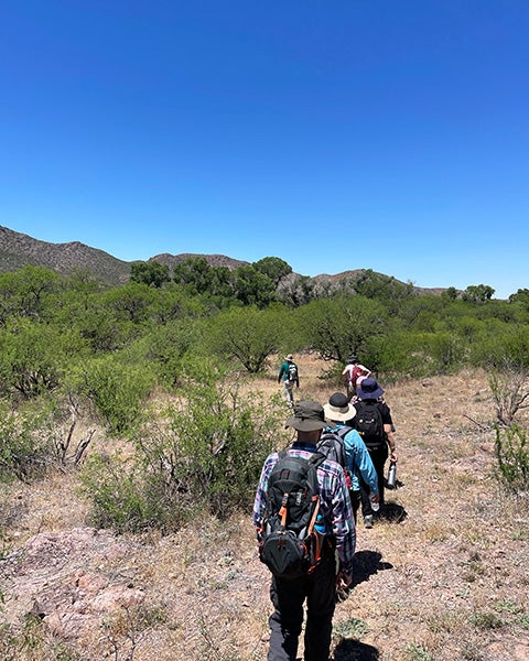 People hike a hilly dry terrain