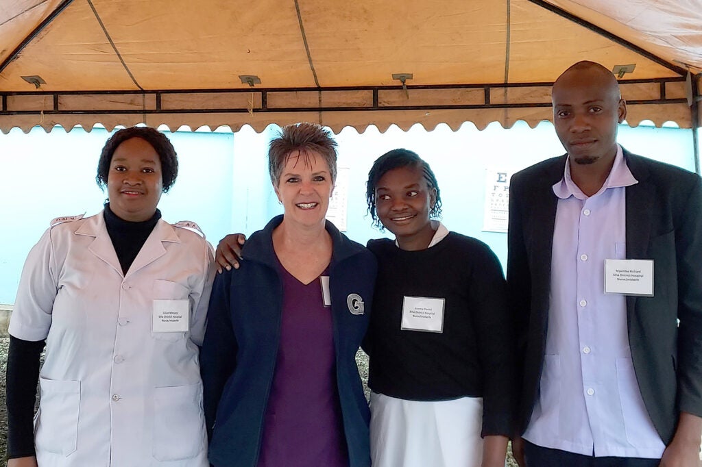 Krista Smith with four hospital personnel stand together under a tent canopy