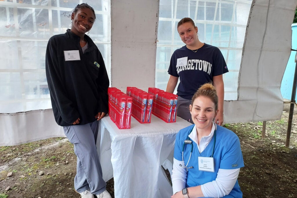 The three students pose with a table displaying new toothbrushes in their packages