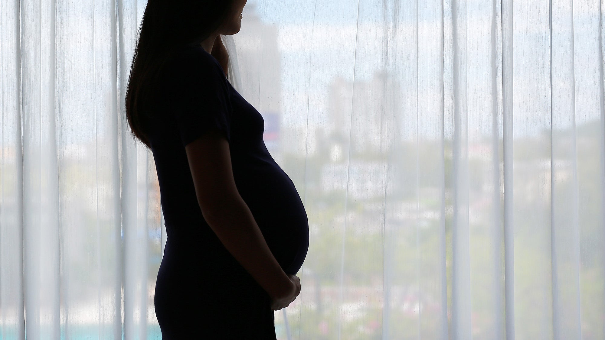 The silhouette of a pregnant woman against a window