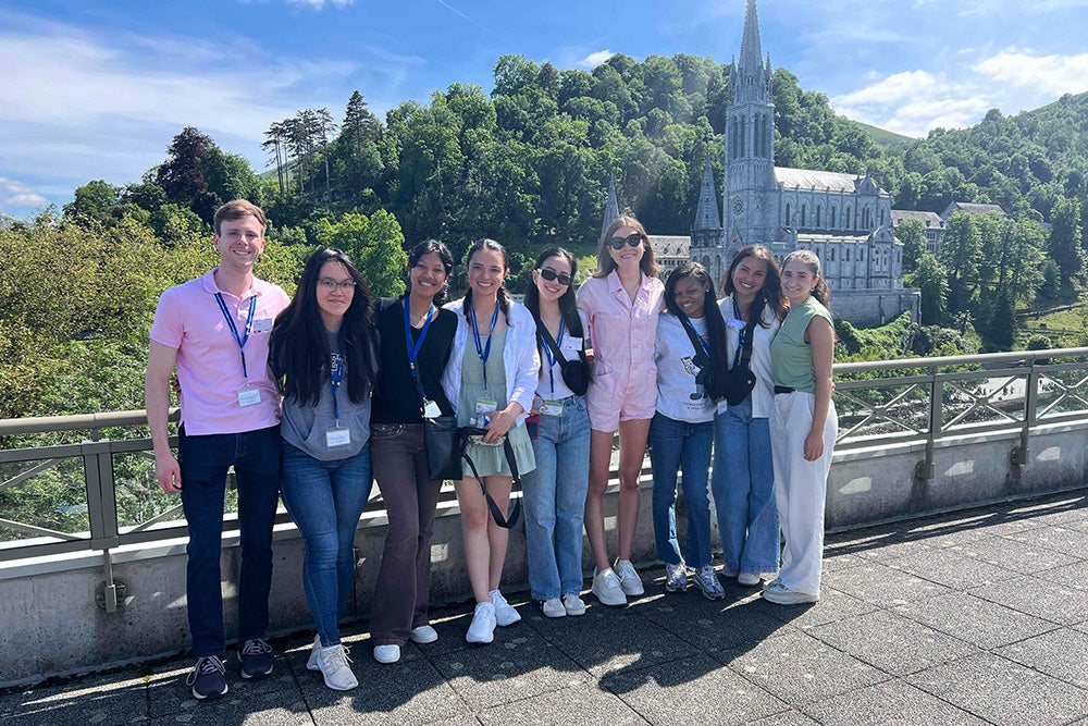 A group of nine students stands with the cathedral in the background