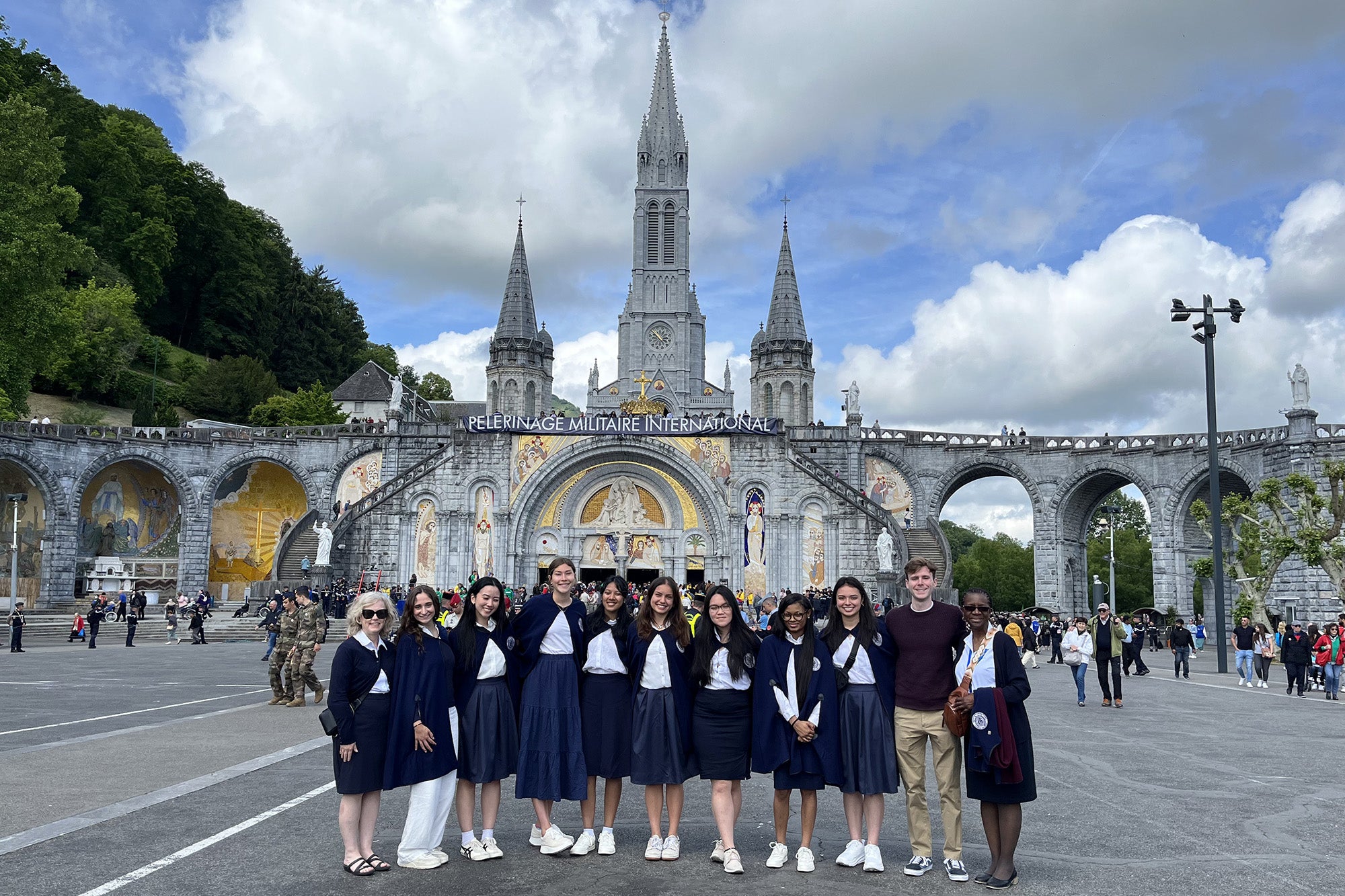 Students stand before the Cathedral at Lourdes and the entrance to the baths