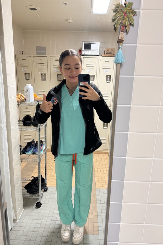 Blackston in scrubs at the hospital giving a thumbs-up sign while taking a mirror selfie