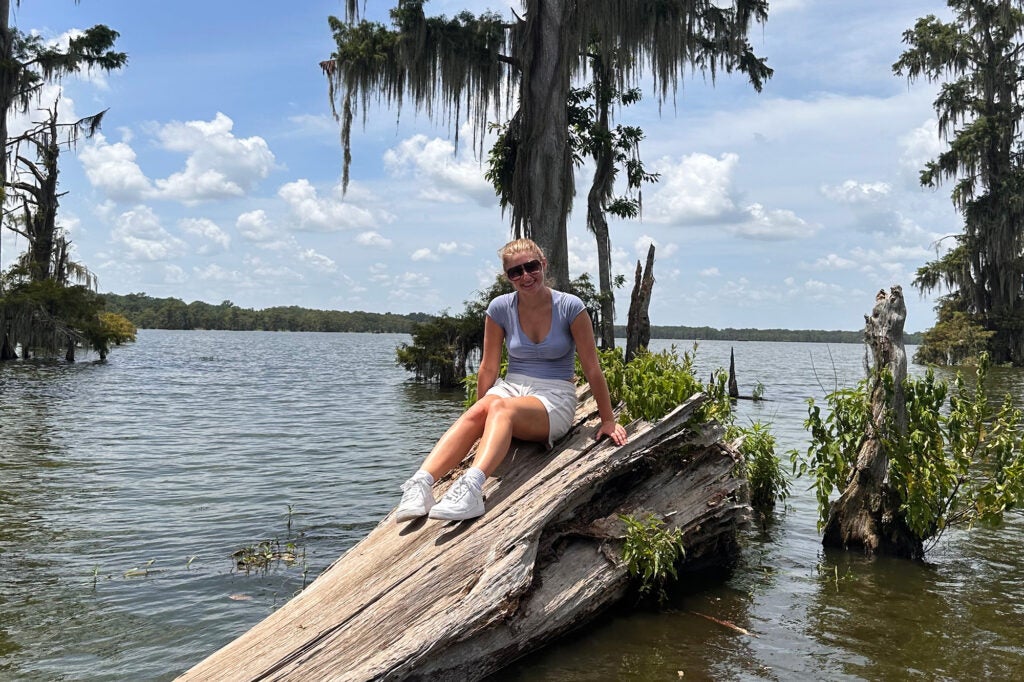 Dombroski sits atop a log in a bayou area