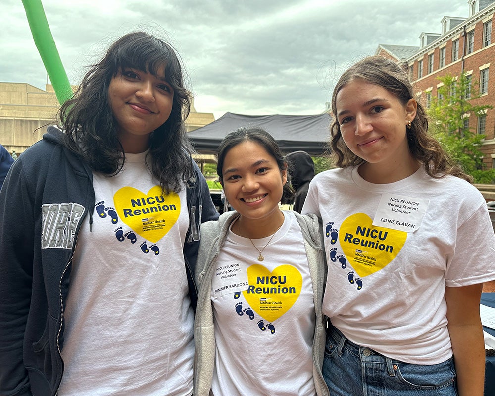 Three nursing students stand together wearing NICU Reunion T-shirts