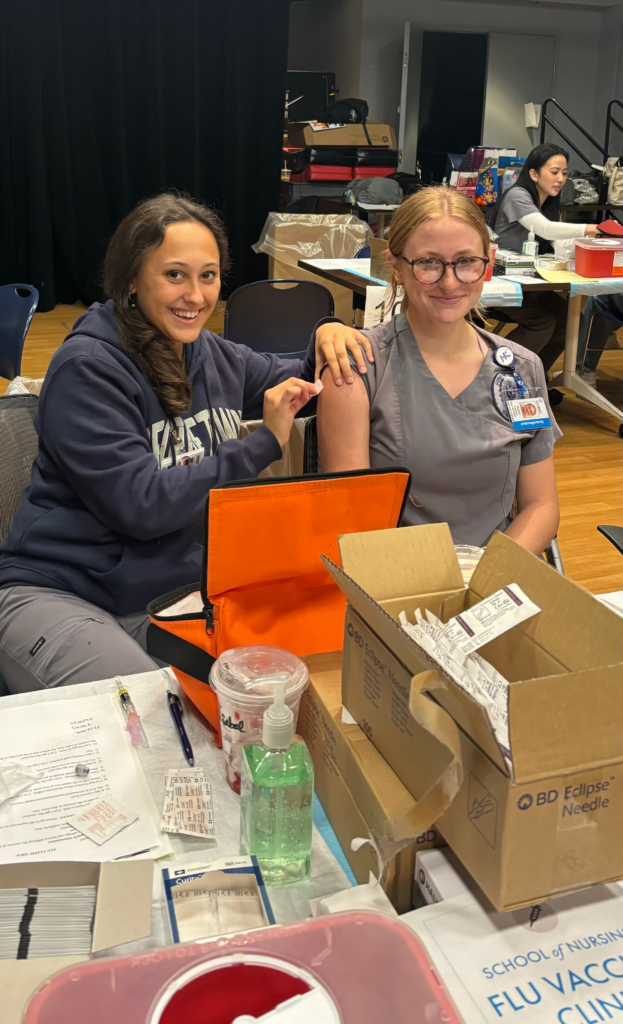 One nursing student administers a flu vaccination to a fellow student. 