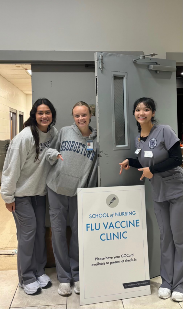 Nursing students gather by a Flu Vaccine Clinic sign on Georgetown's campus.