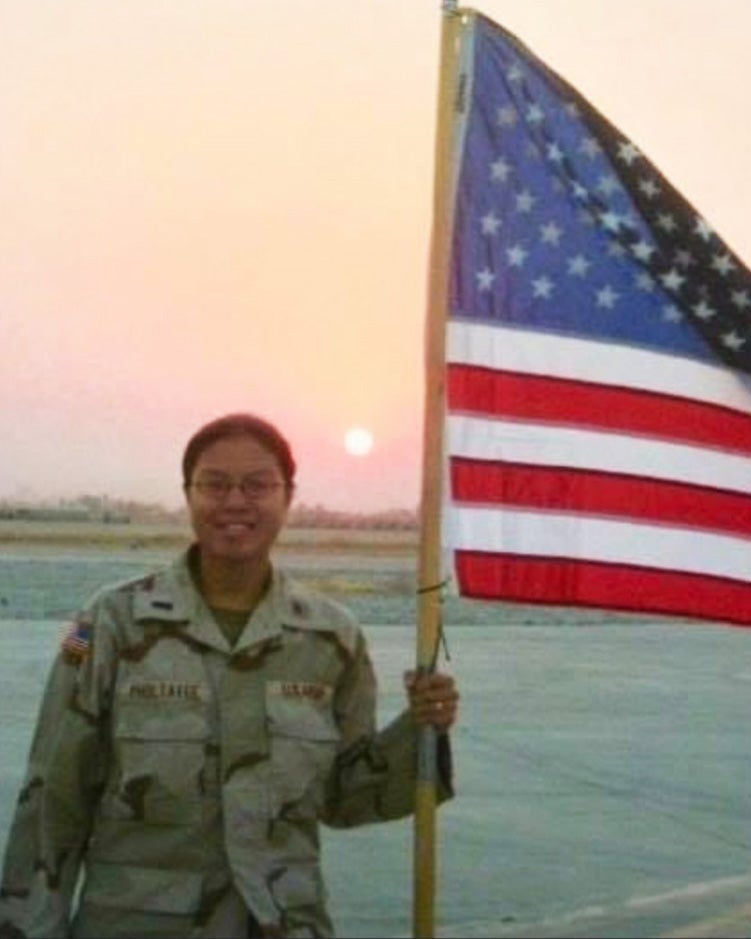 Paruchabutr wears Army khakis and holds an American flag amid the Iraqui landscape