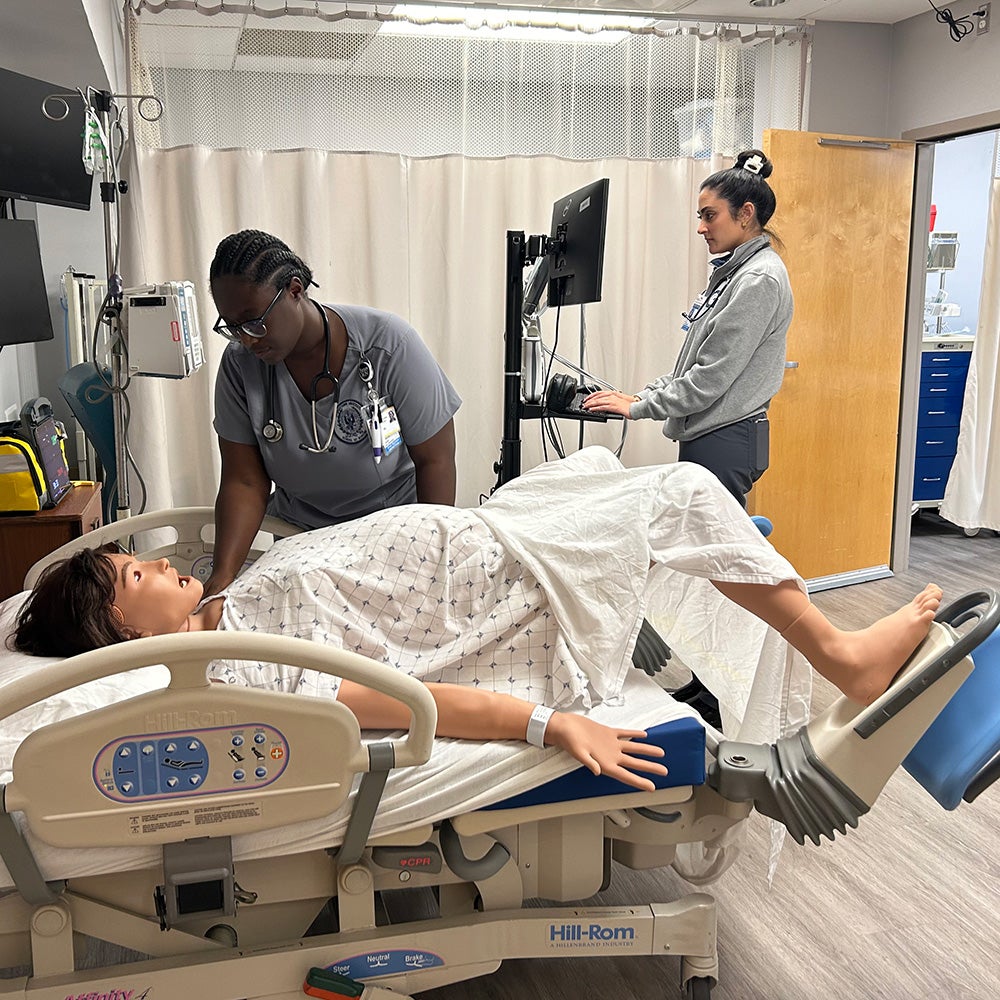 Two students monitor a simulated patient in labor