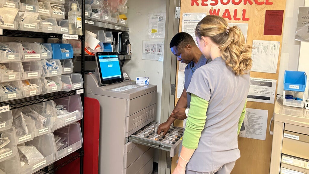 Two individuals work with a medication dispenser