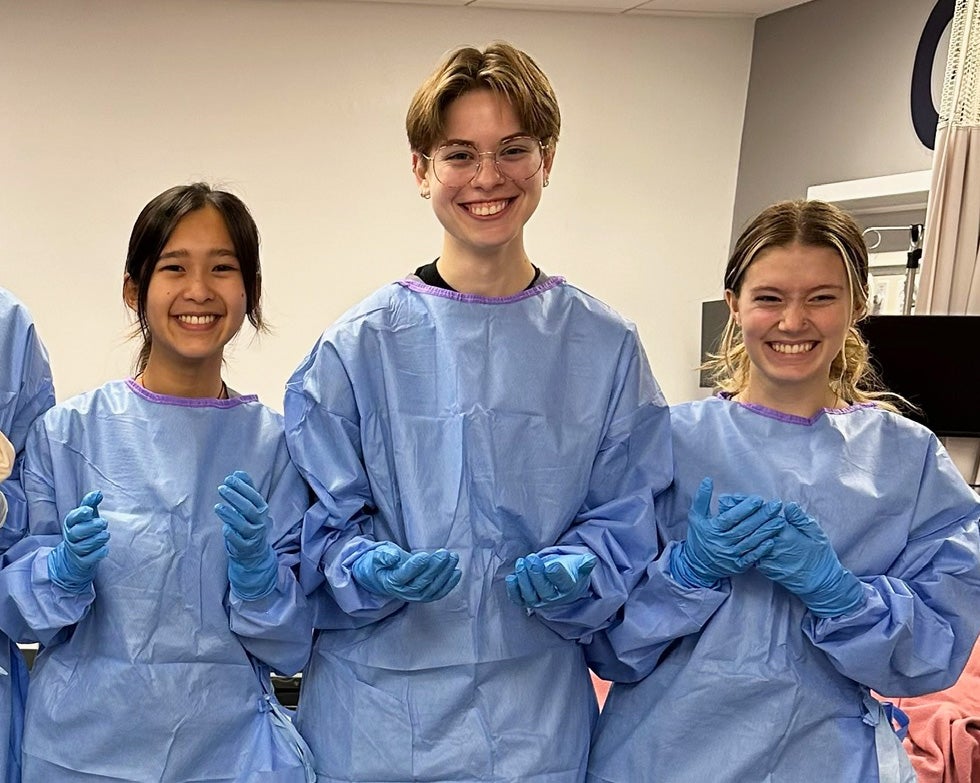 Three students in surgical garb stand together