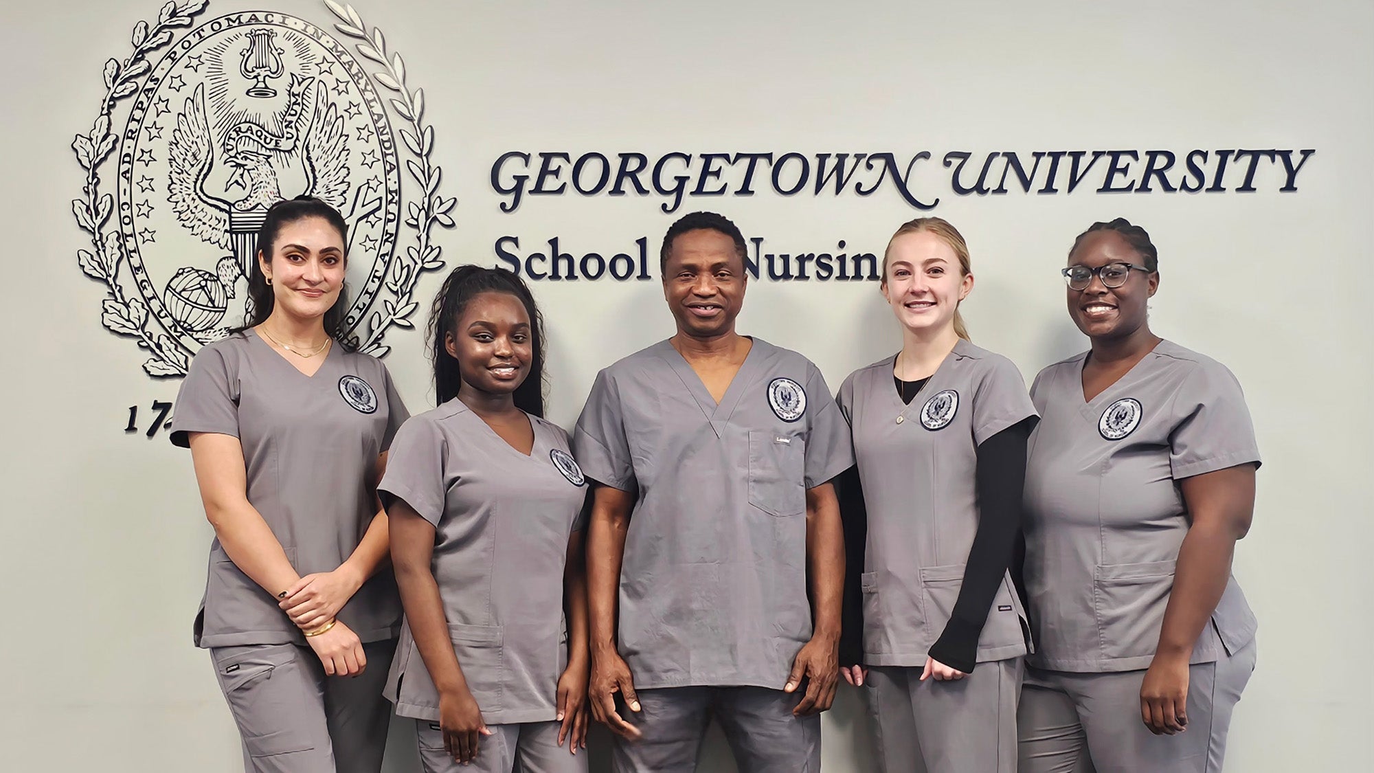 The five Washington Home scholarship winners stand together with the logo of the School of Nursing behind them on the wall