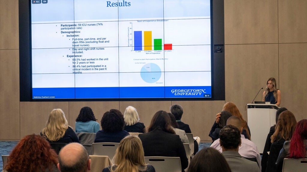 A student presents her project before an audience in an auditorium