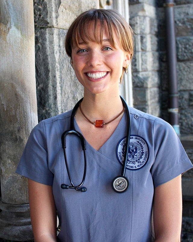 Lexie Meger in gray School of Nursing scrubs with a stethoscope draped around her neck